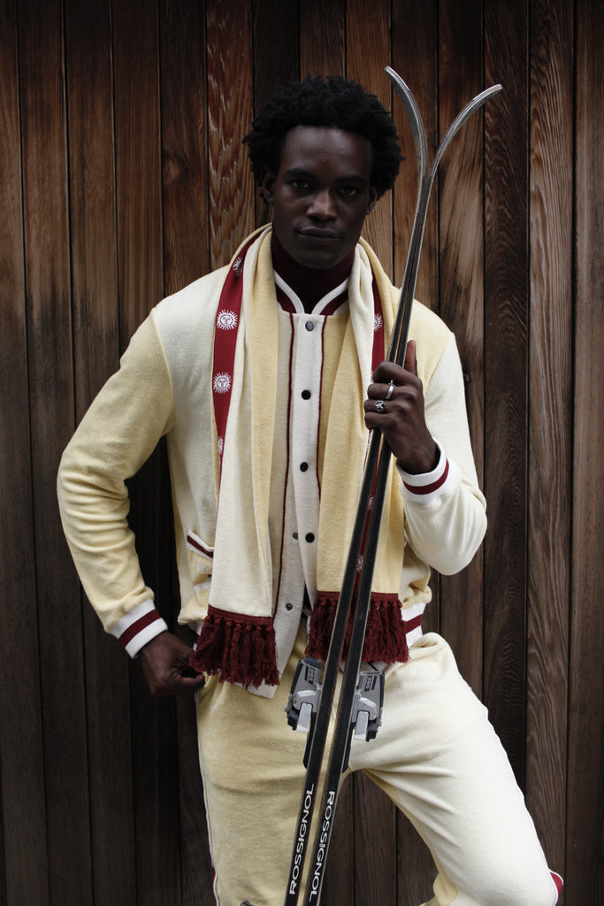 Male model holding skis in front of wooden wall