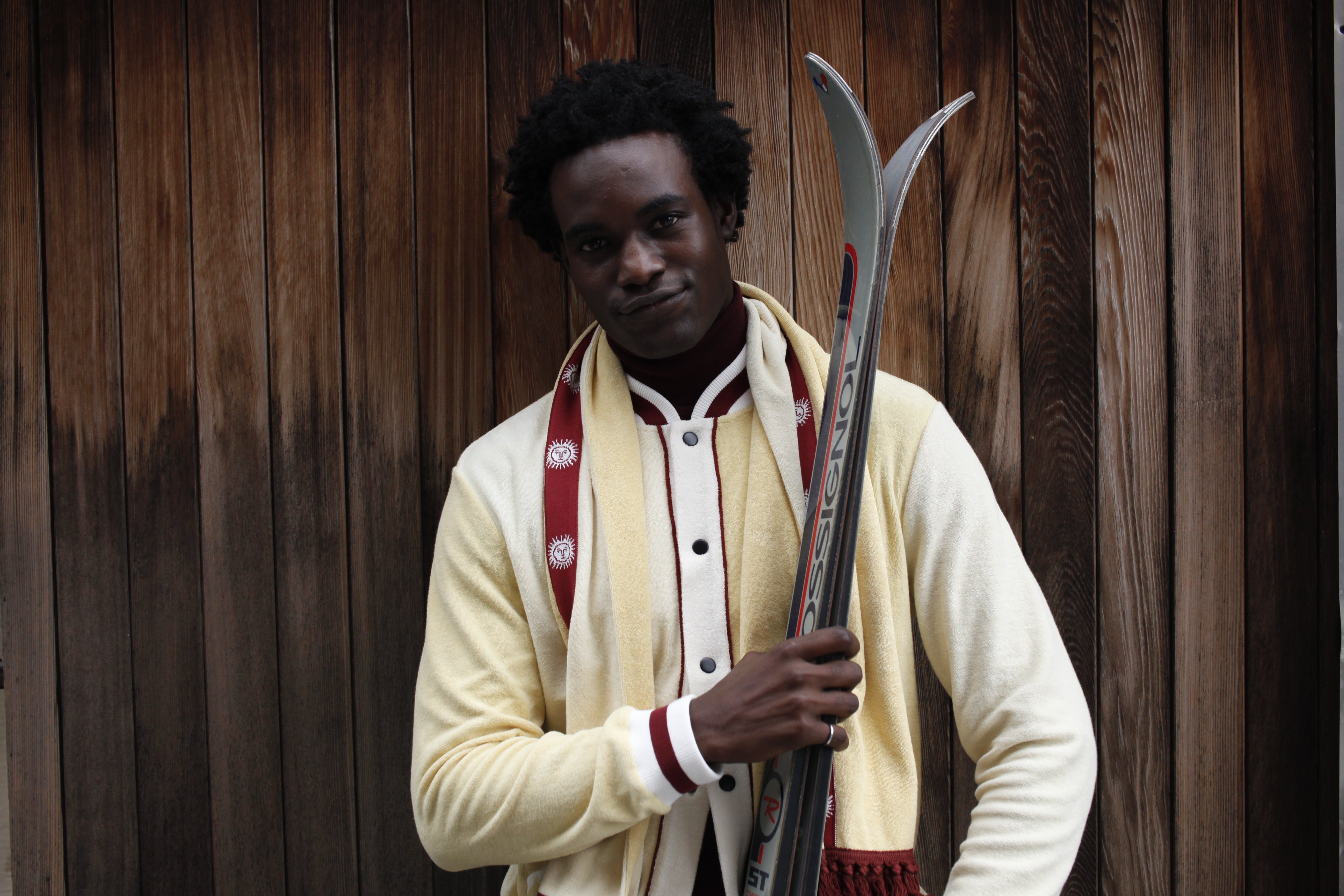 Male model close up holding skis and smiling at camera