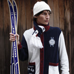 Male model in set with scarf holding a pair of skis