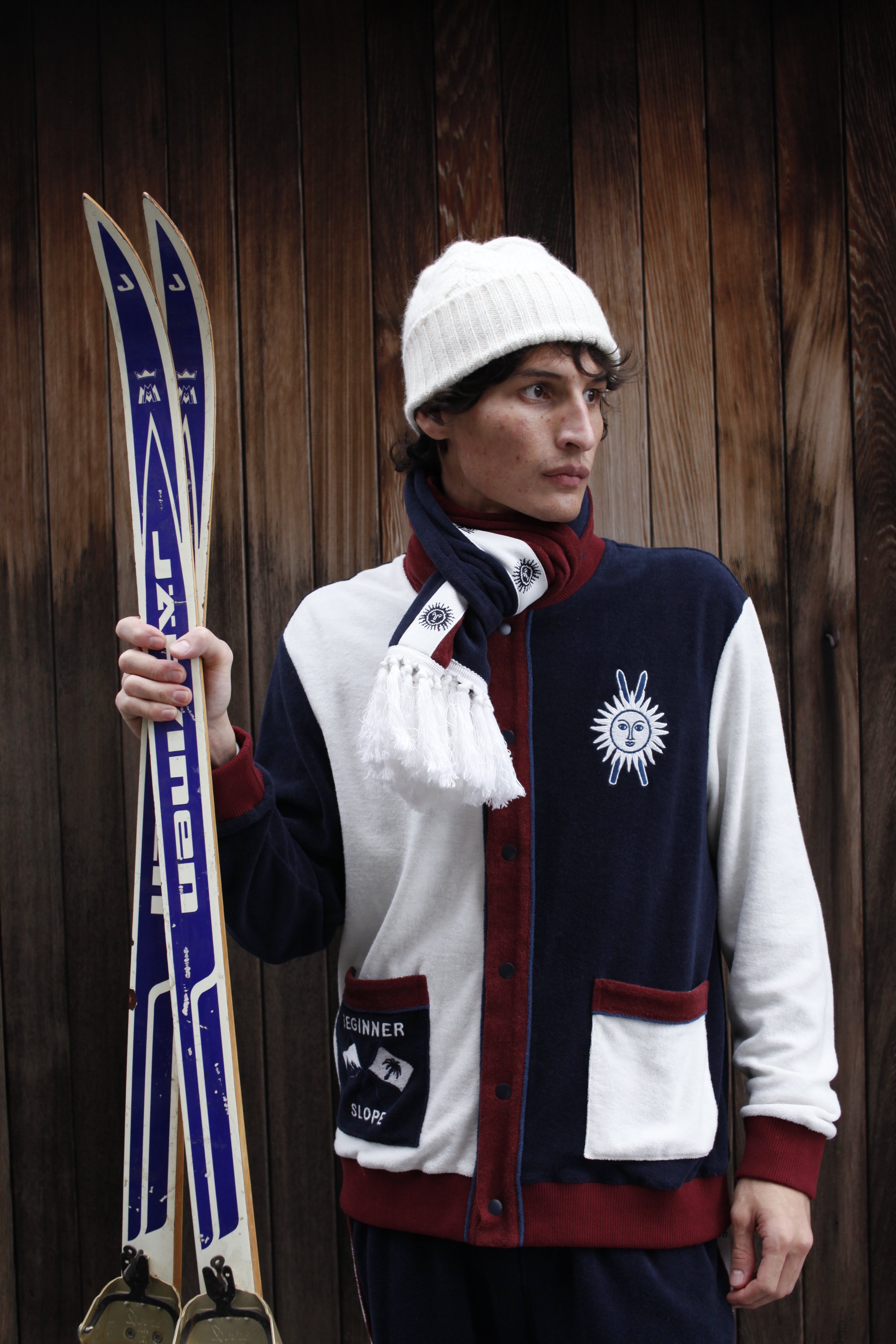 Male model in set with scarf holding a pair of skis