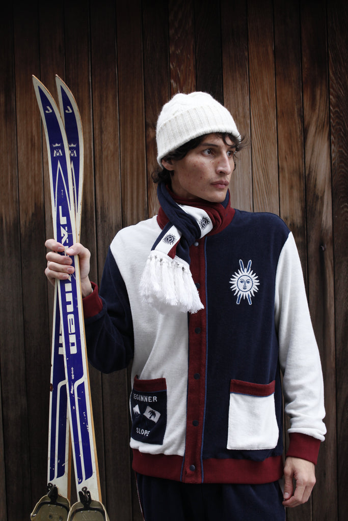 Male model in set with scarf holding a pair of skis