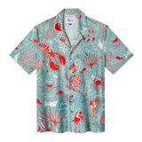 Front flat lay view of the shirt showing an array of semi-nude revelers making music among encouraging semi-tame sea creatures, with white piping, including V pocket, and the Print is matched on the pocket and across the front opening 