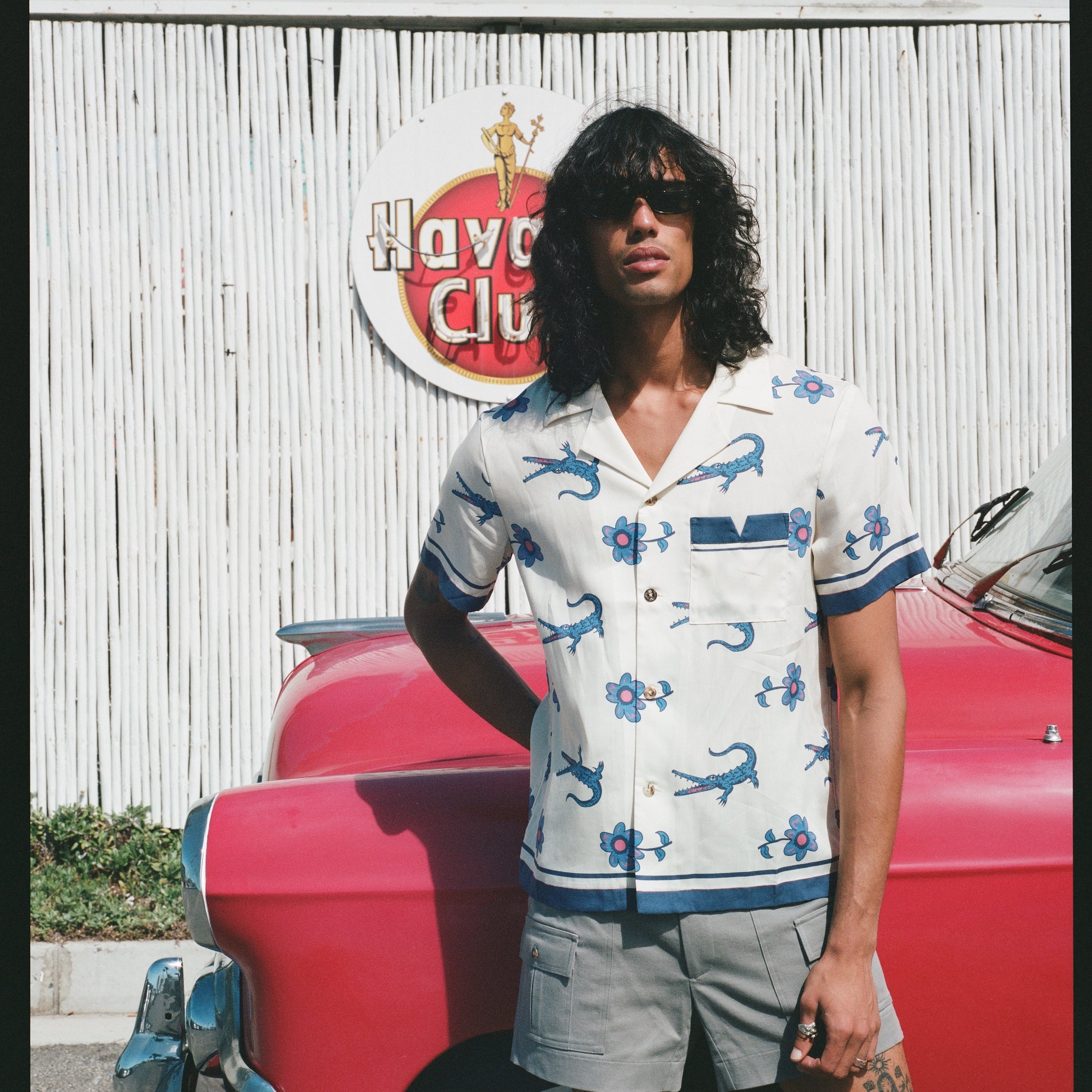 Male model wearing the shirt leaning on a red car