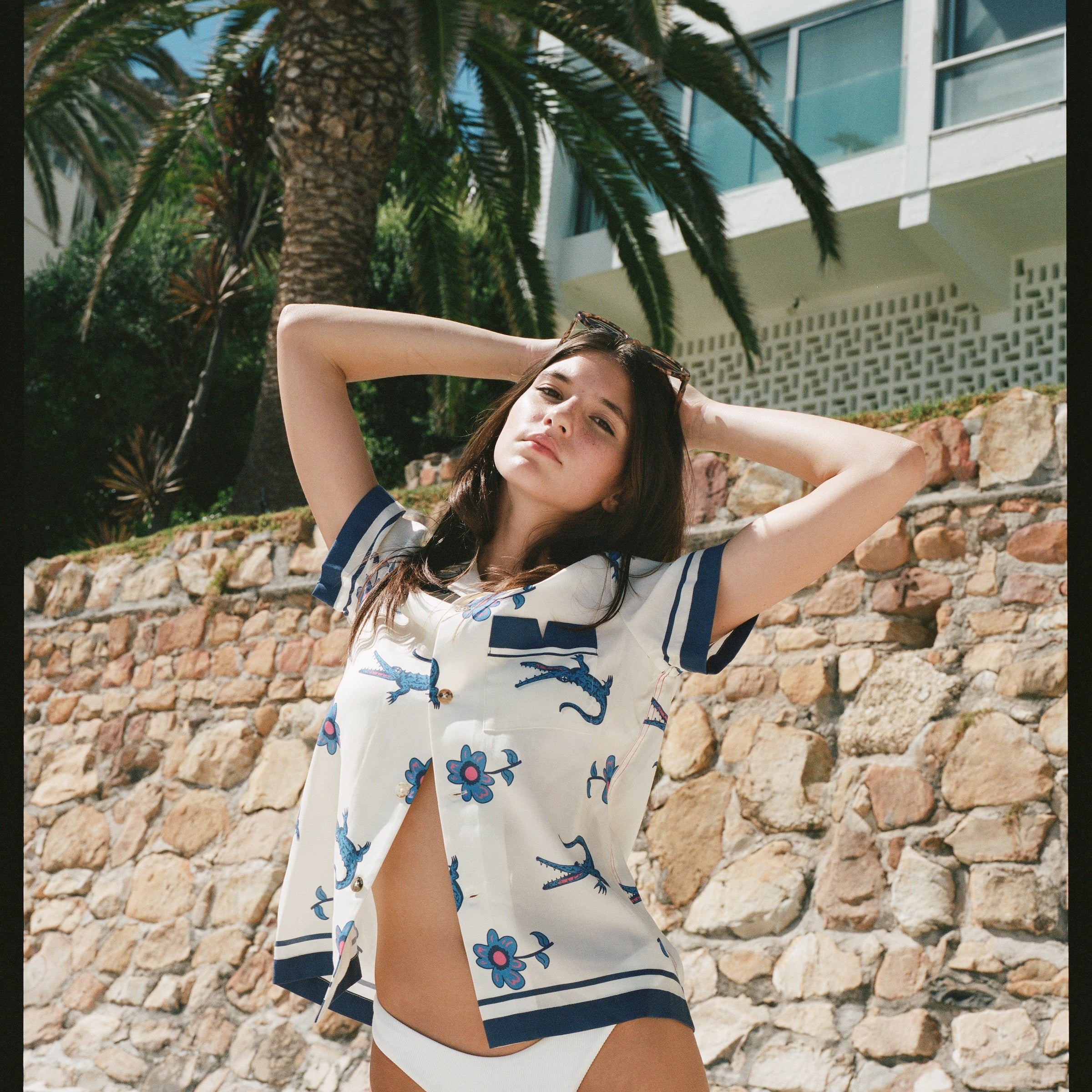 Female model posing in shirt with bottom buttons undone over a bikini