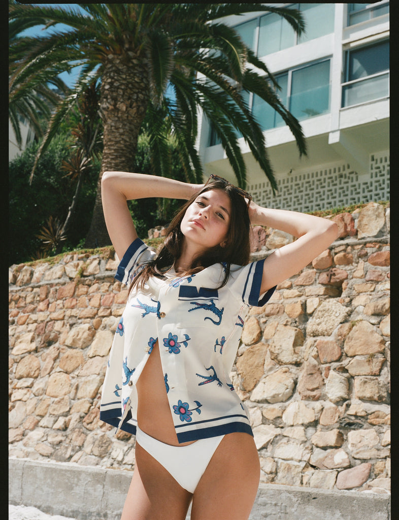 Female model posing in shirt with bottom buttons undone over a bikini