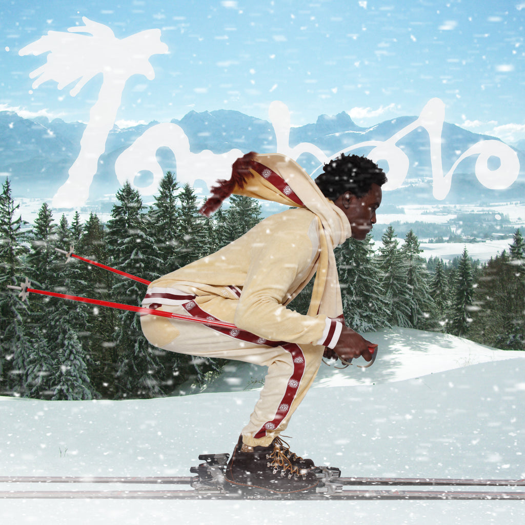Male model mock skiing in front of a fake snowy scene in full set