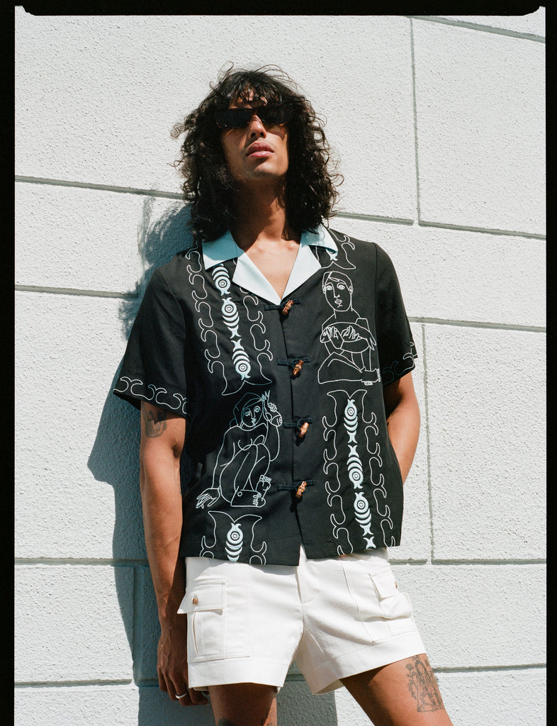 model leans against wall in sunglasses