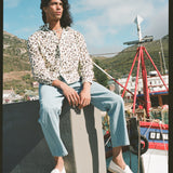 Male model sitting on a ledge in the shirt and linen pants