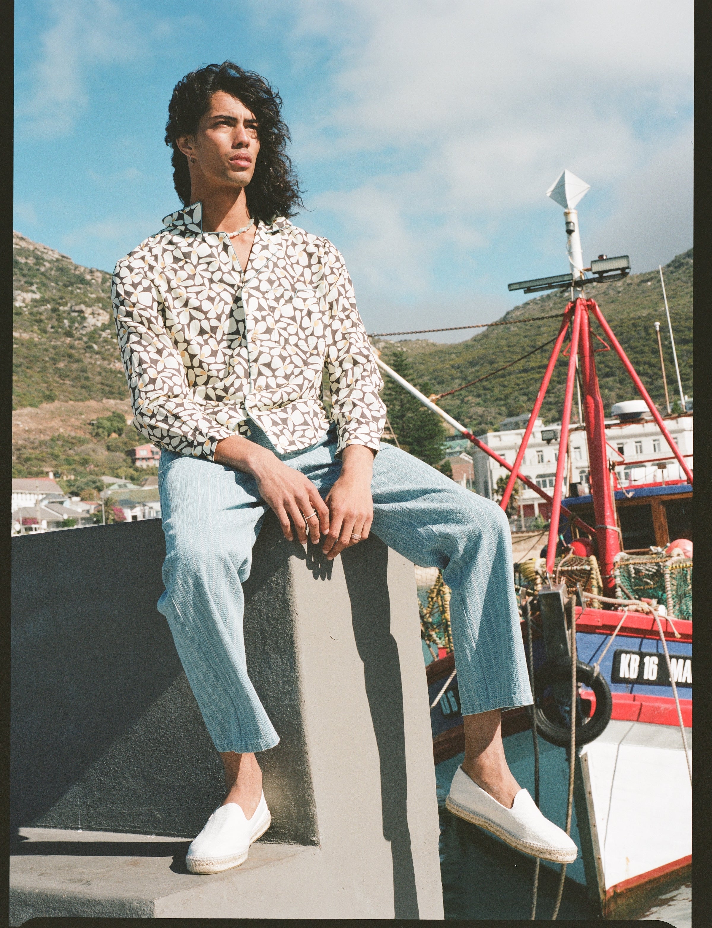 Male model sitting on a ledge in the shirt and linen pants
