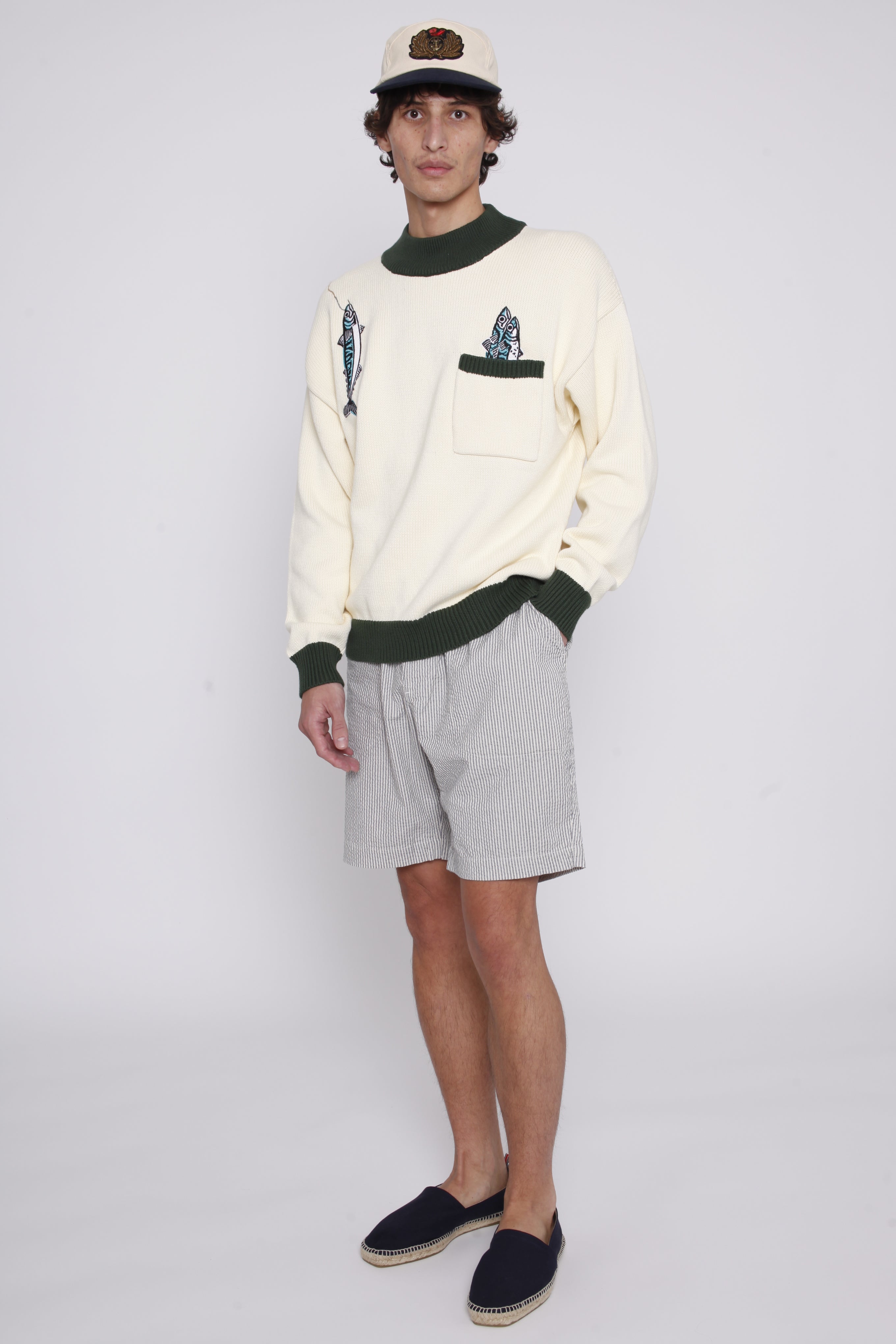 Male model wearing the angler sweater with shorts and a hat