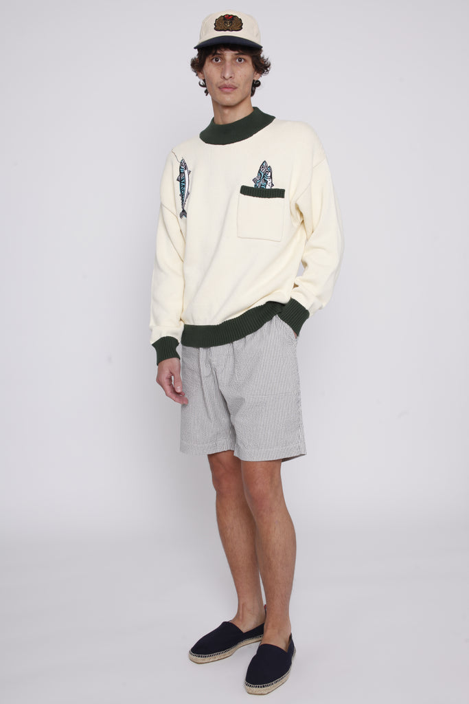 Male model wearing the angler sweater with shorts and a hat