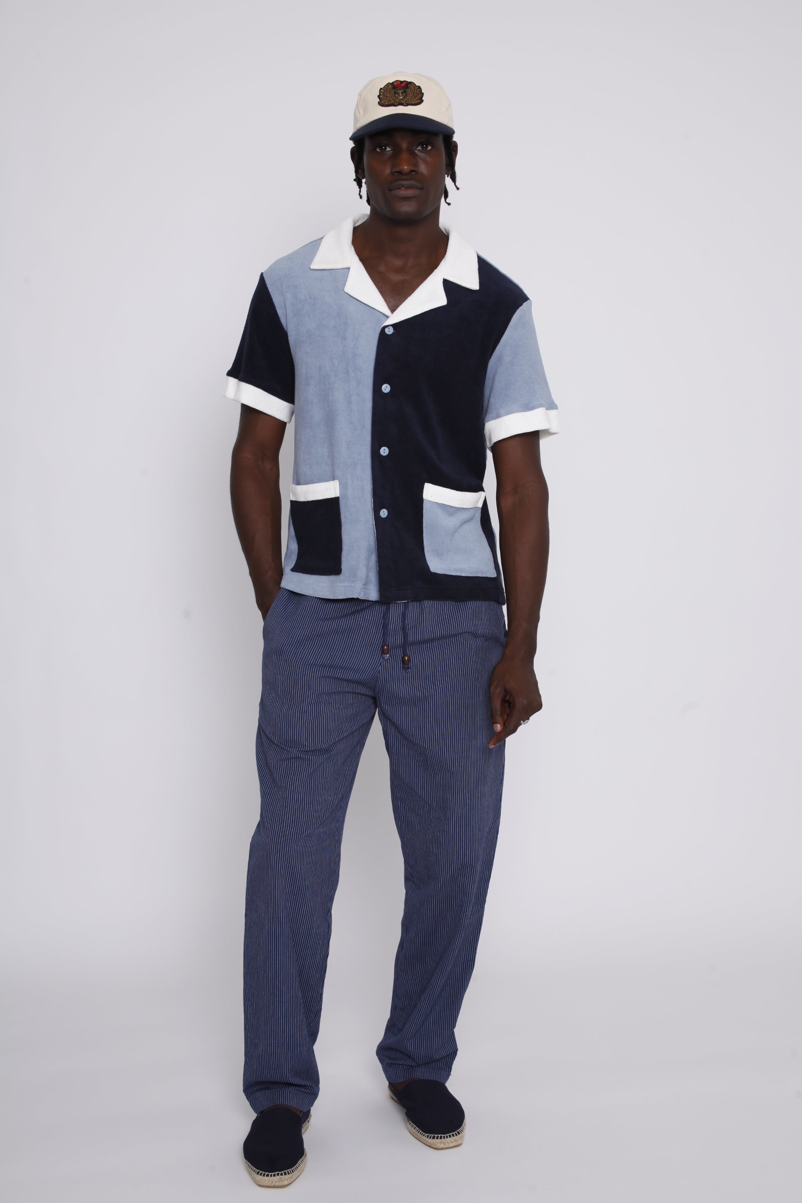 Full body view of male model wearing cap with blue two toned polo with pants