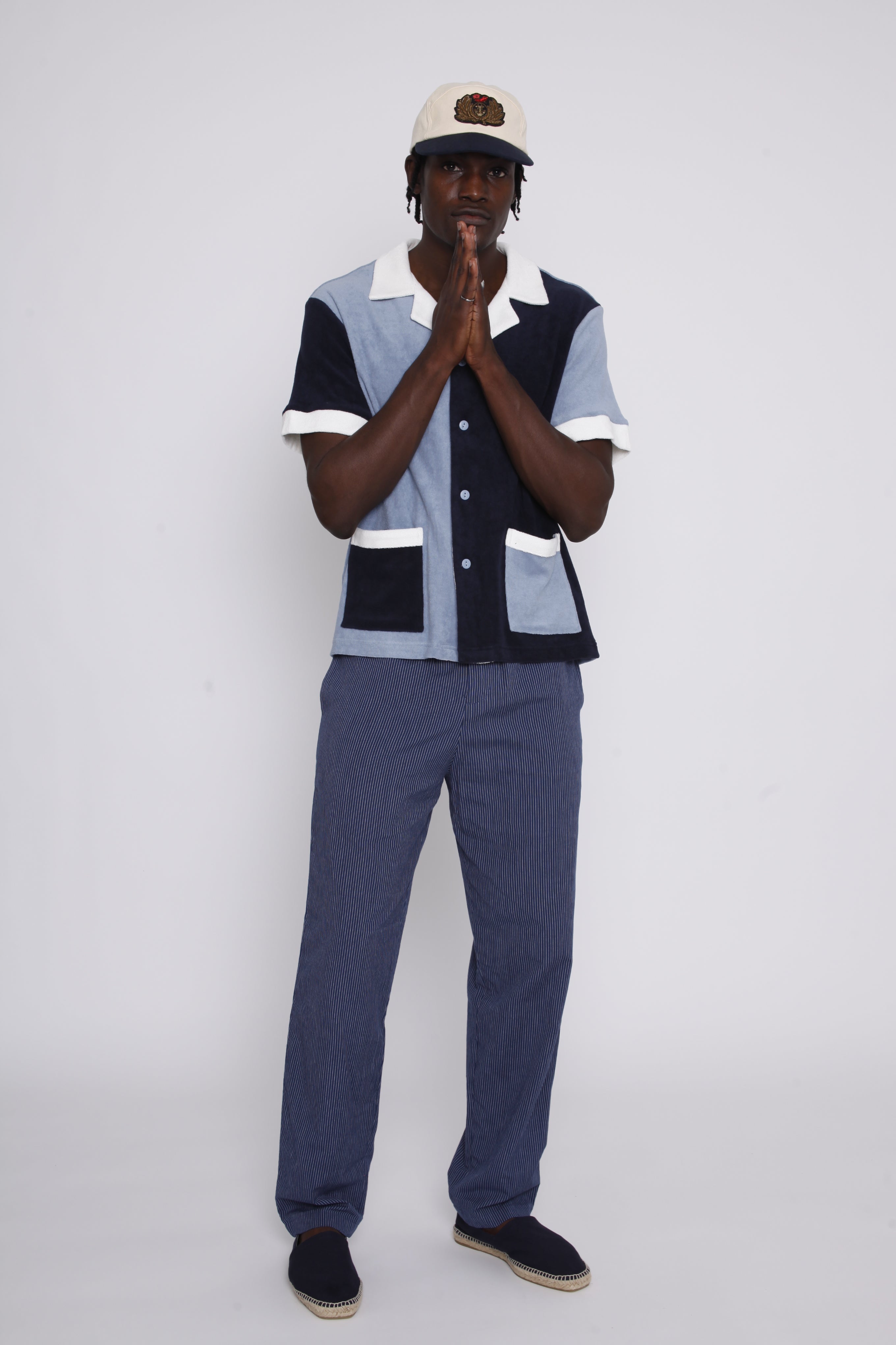 Male model wearing cap posing in studio with hands clasped in prayer in front of his mouth