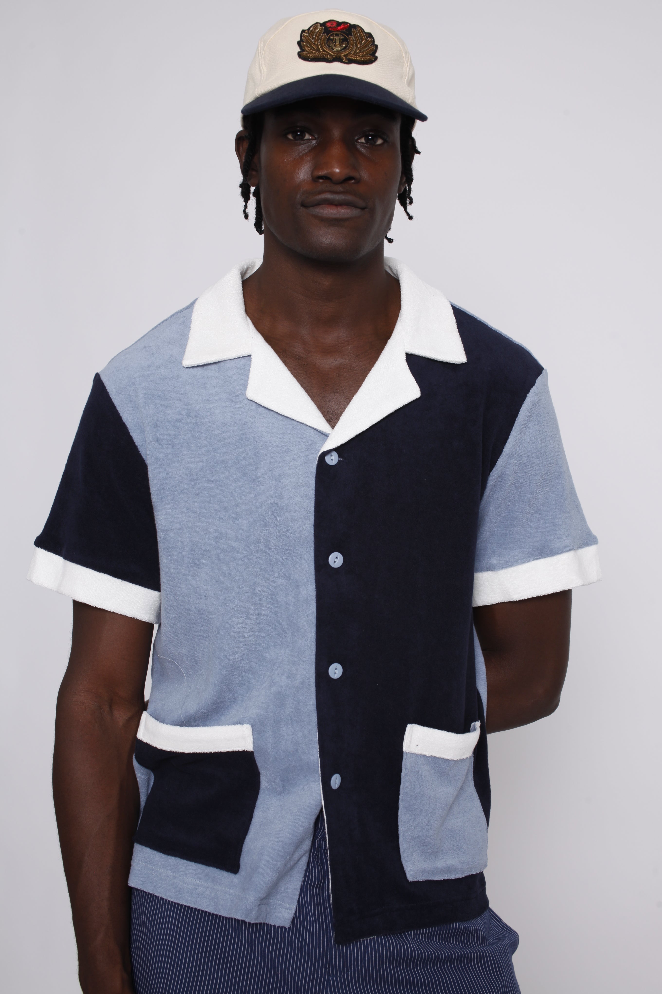 male model wearing shirt with tombolo hat and blue pants