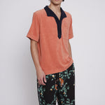 male model wearing apricot polo with hand in pants pocket