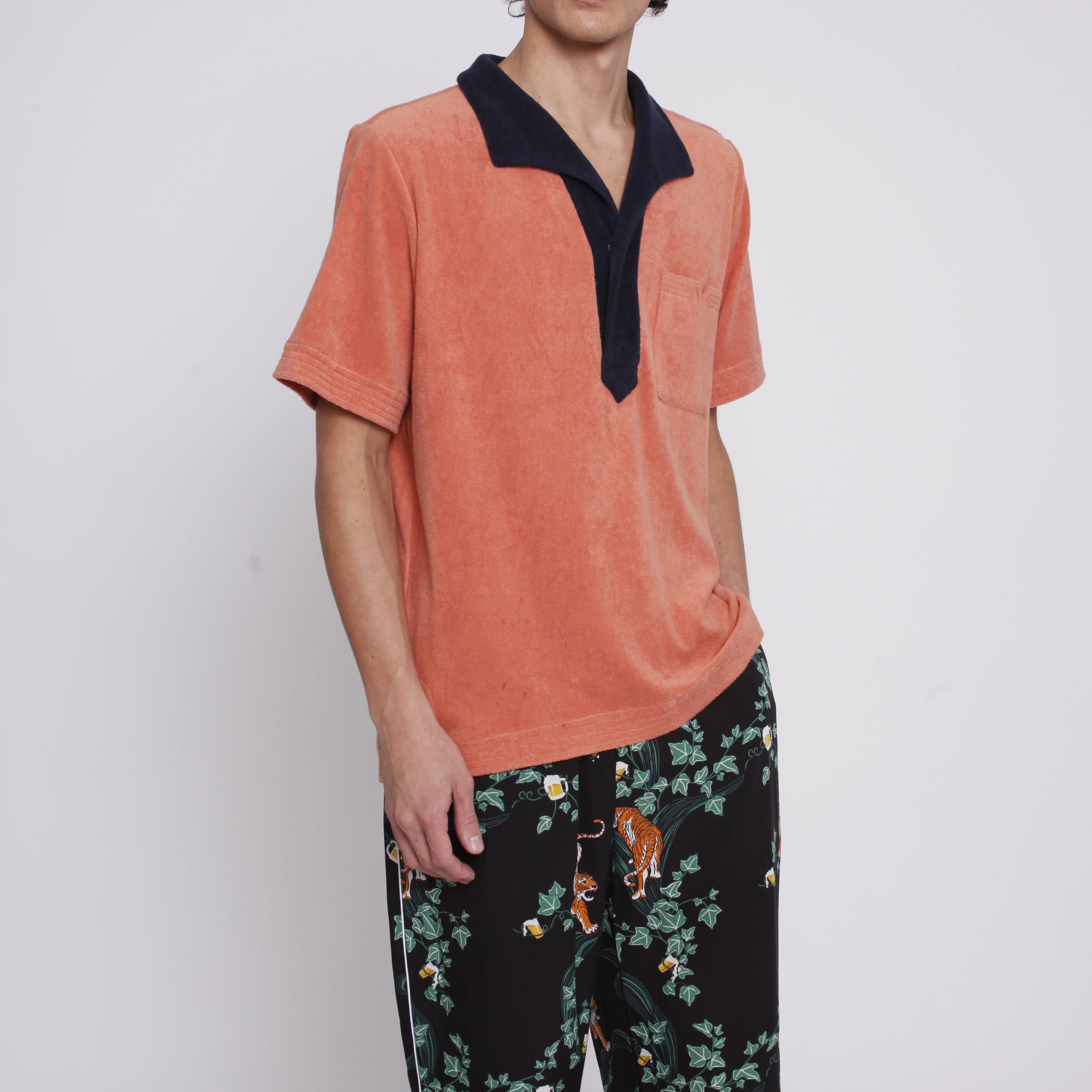 male model wearing apricot polo with hand in pants pocket