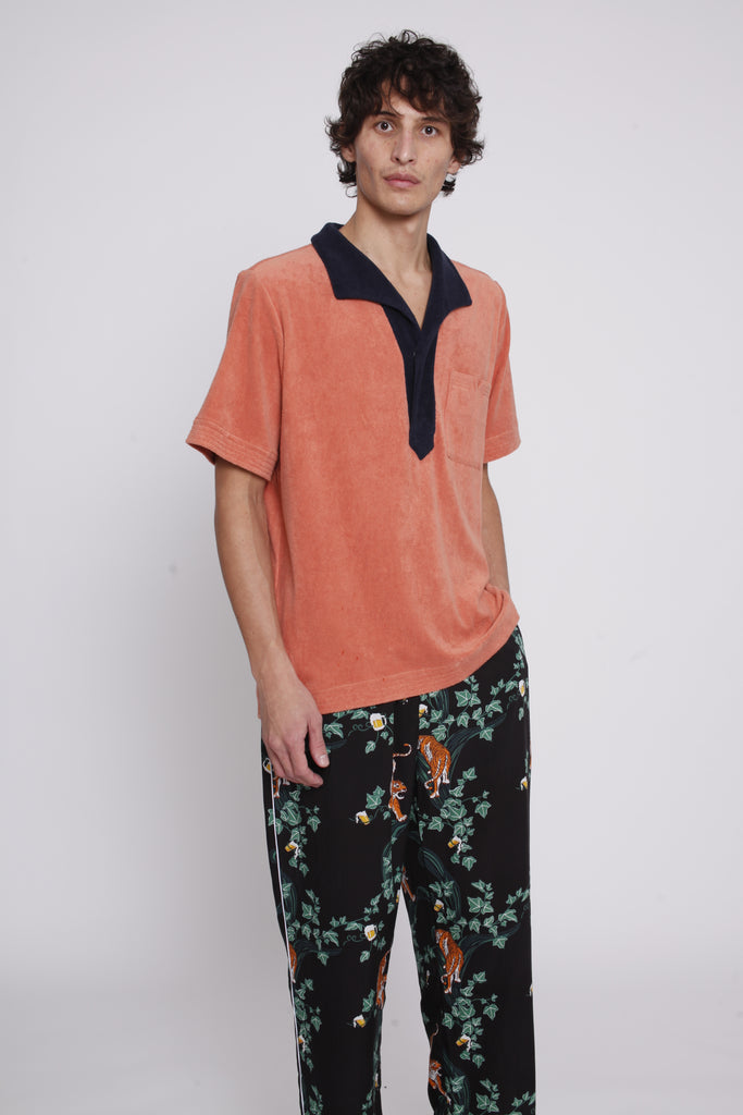 male model wearing apricot polo with hand in pants pocket