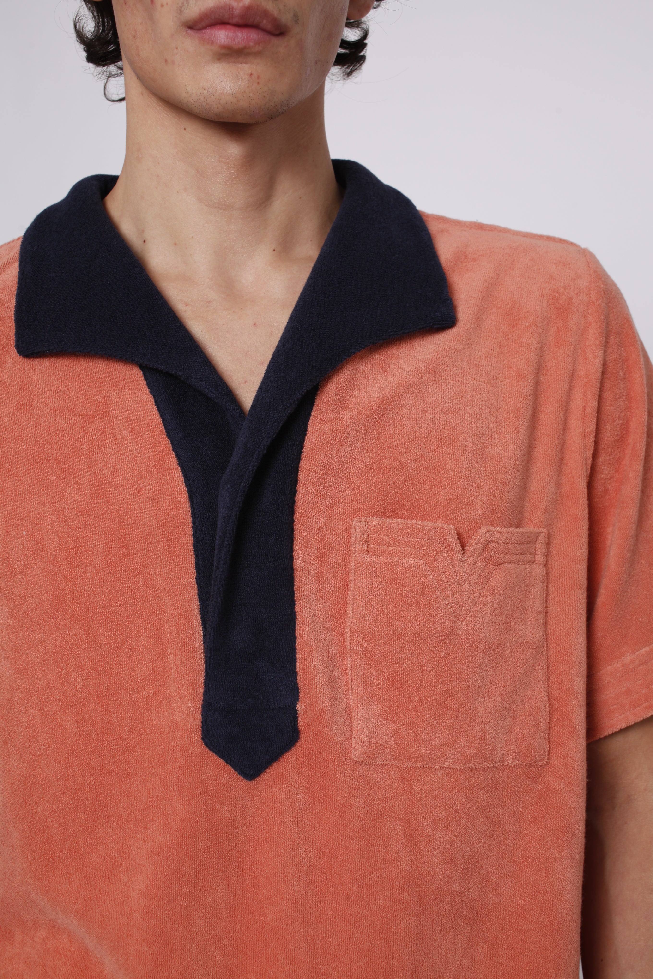 Close up of navy collar and apricot v cut pocket on male model