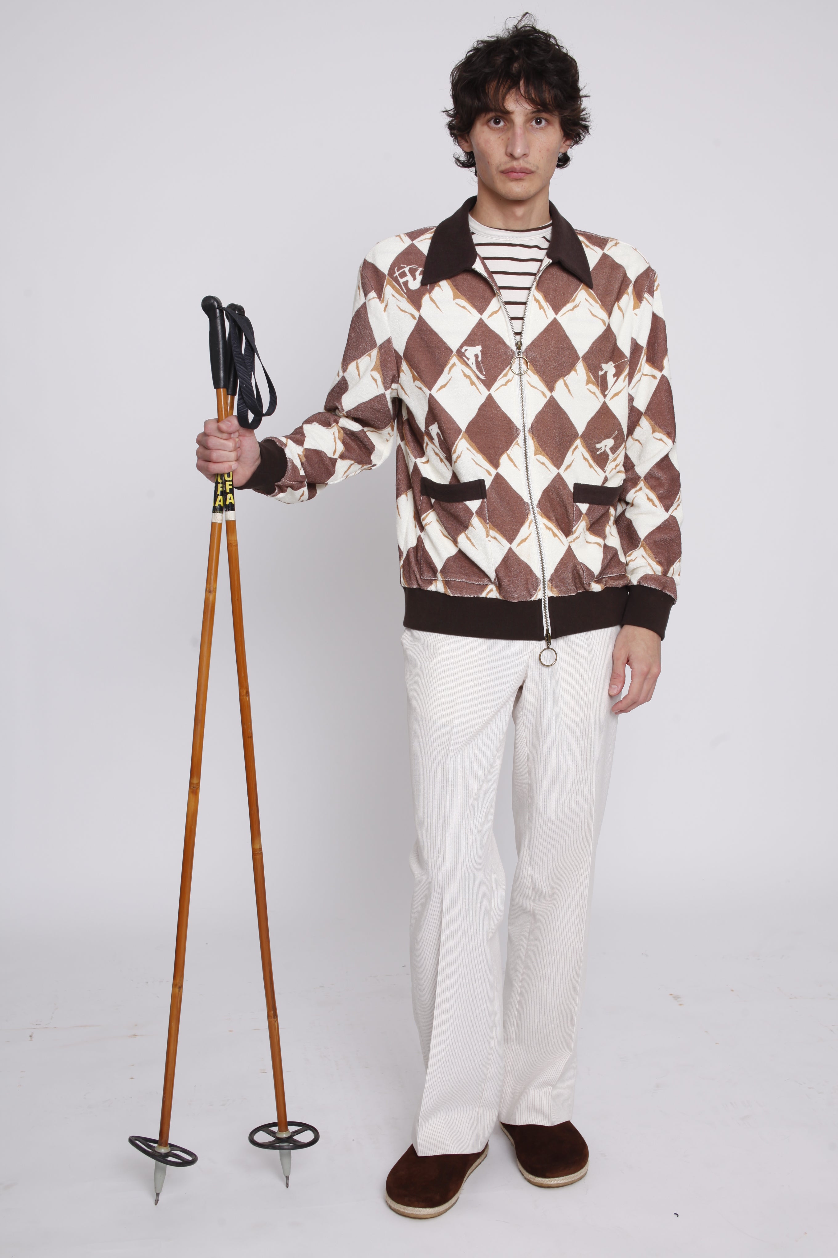 Man holding ski poles stares at camera