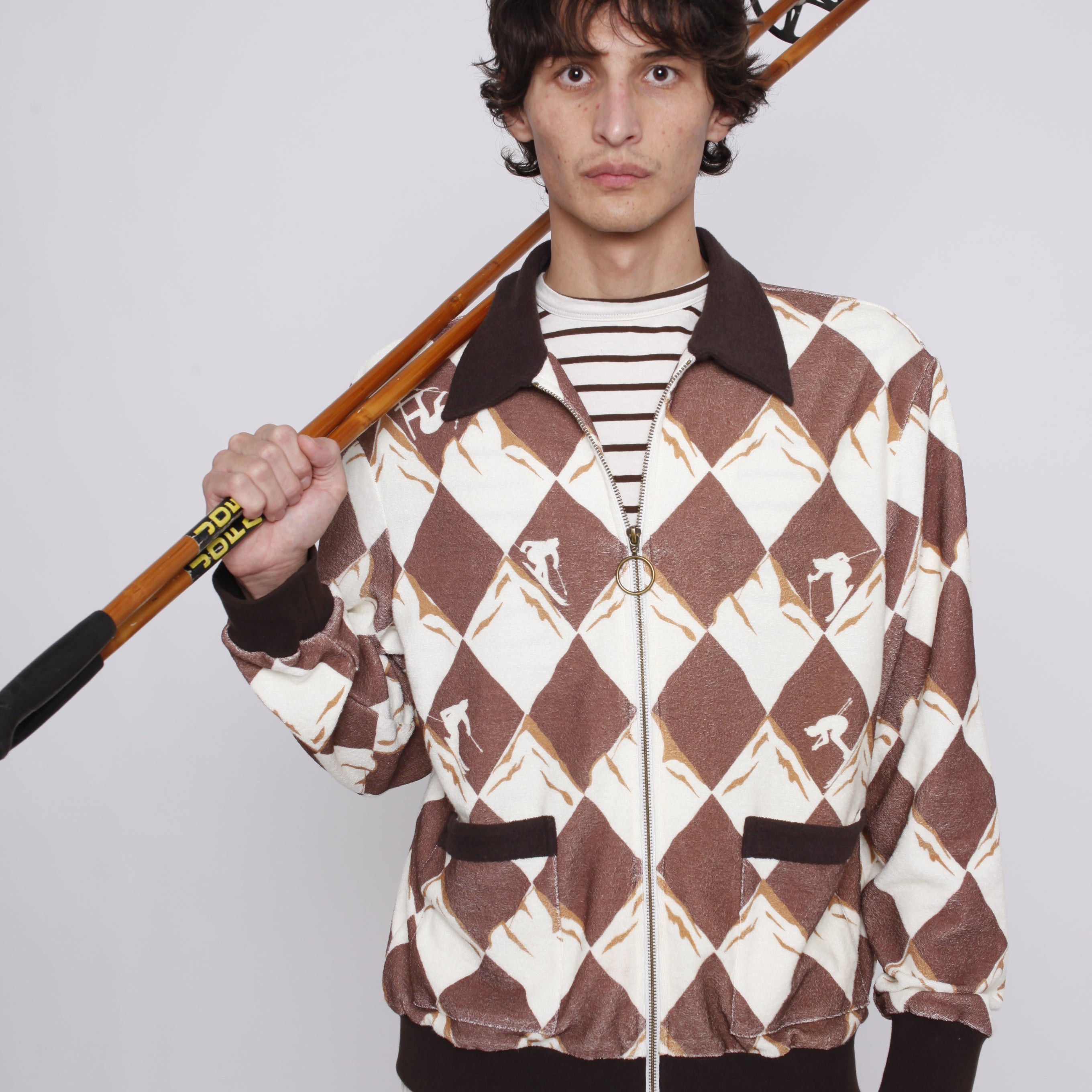 Man rests ski poles on his shoulder as he stares at camera