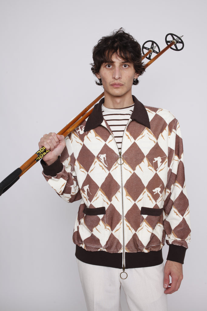 Man rests ski poles on his shoulder as he stares at camera