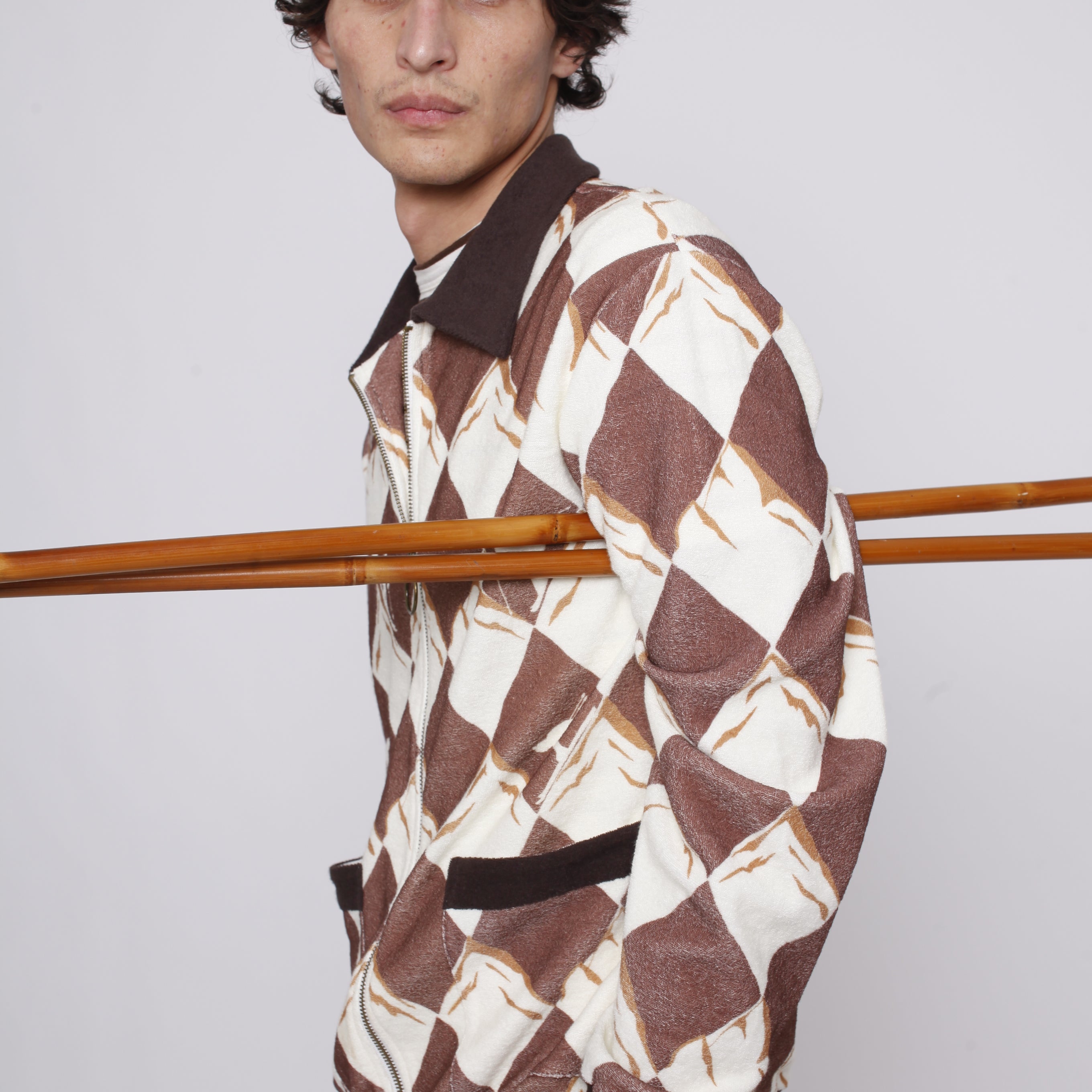 Man poses side on with ski poles under his arm and hand in pocket