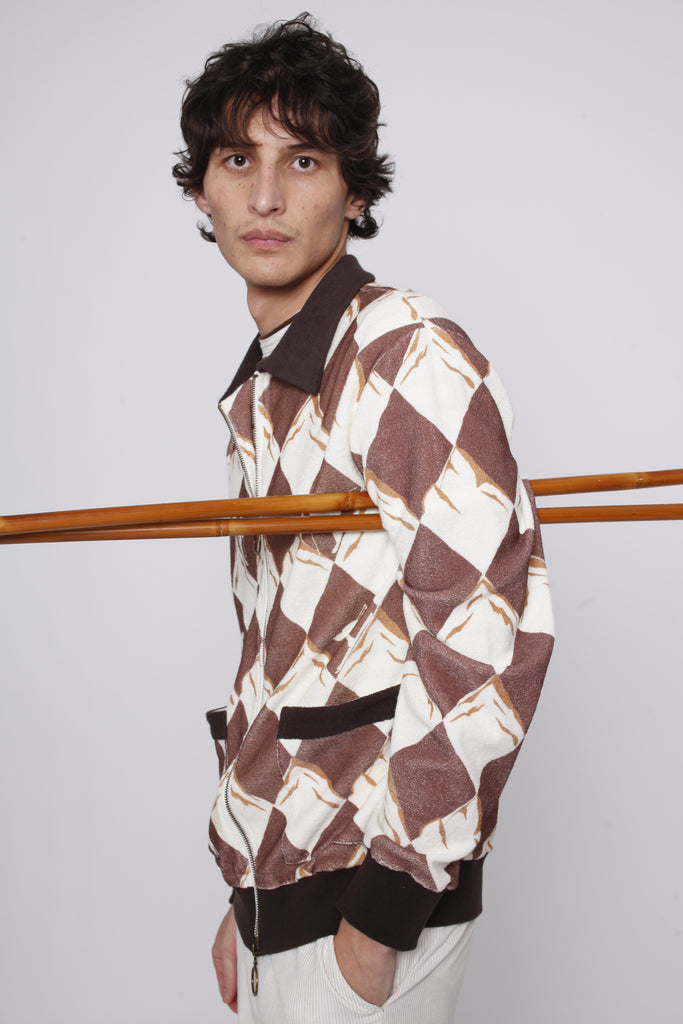 Man poses side on with ski poles under his arm and hand in pocket