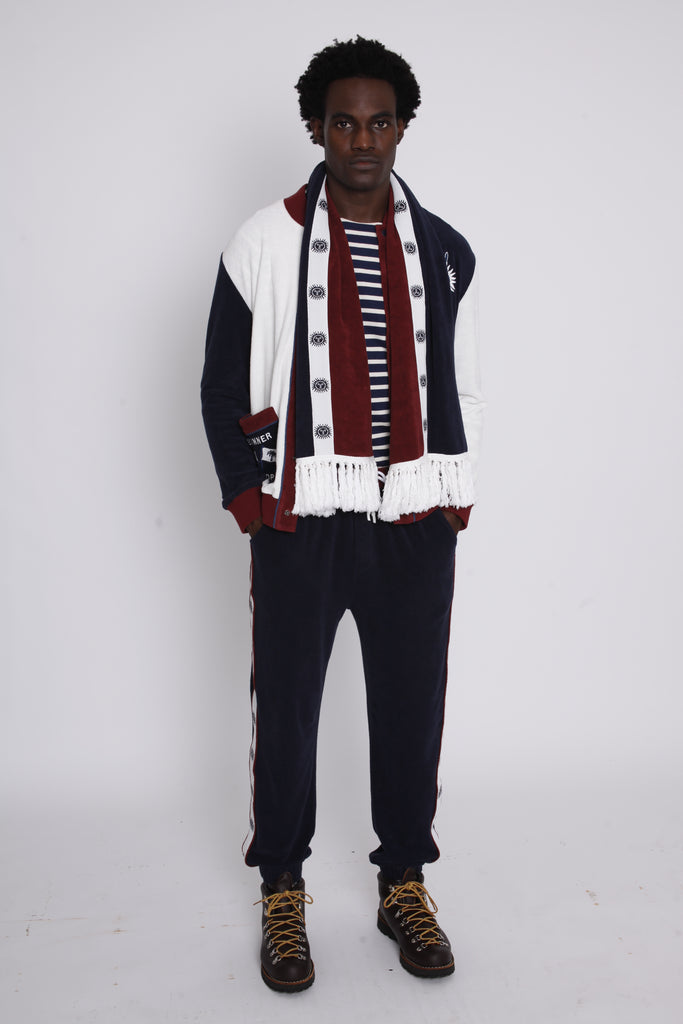 male model in studio with hands in pants pockets and scarf draped over neck