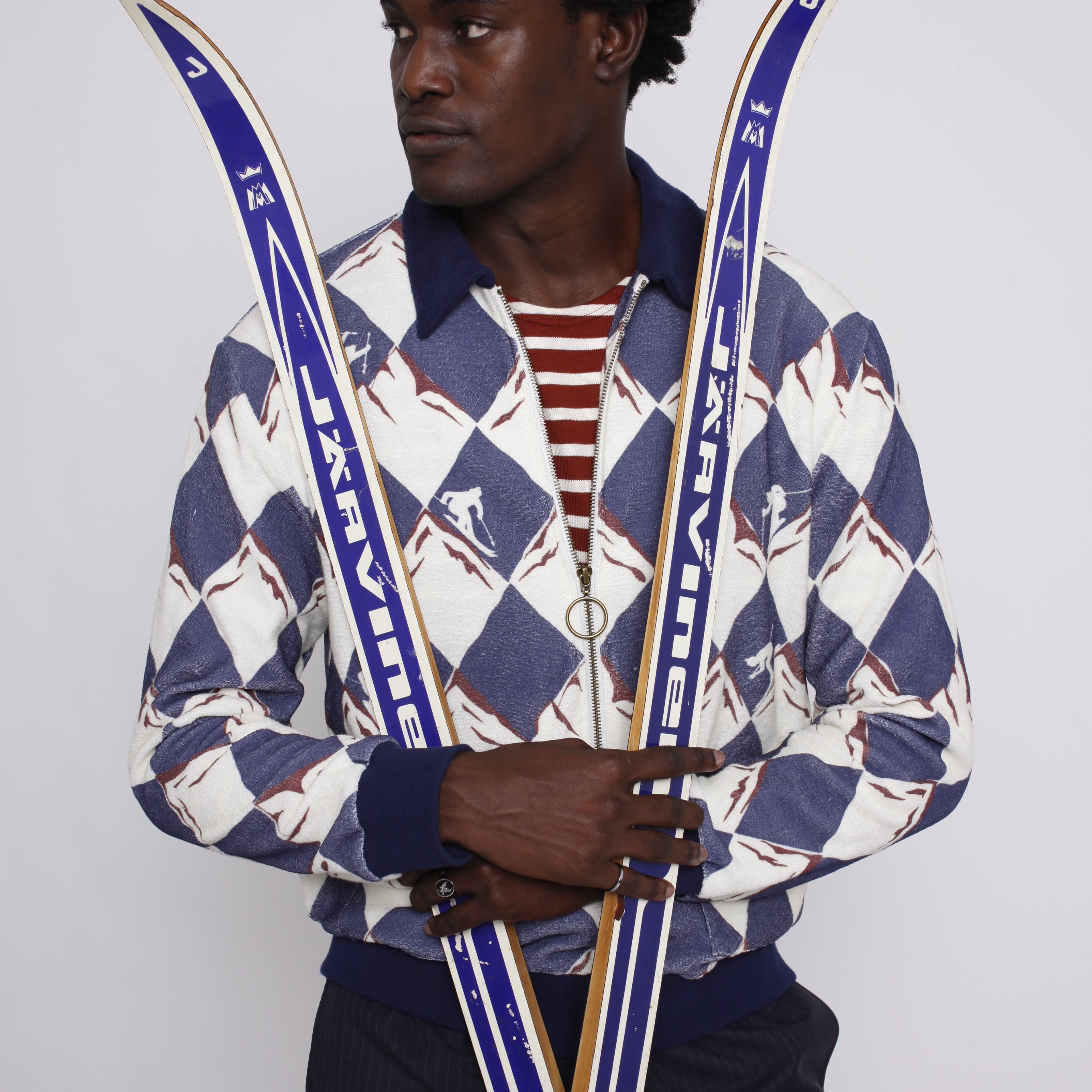 male model holding a pair of skies across his body