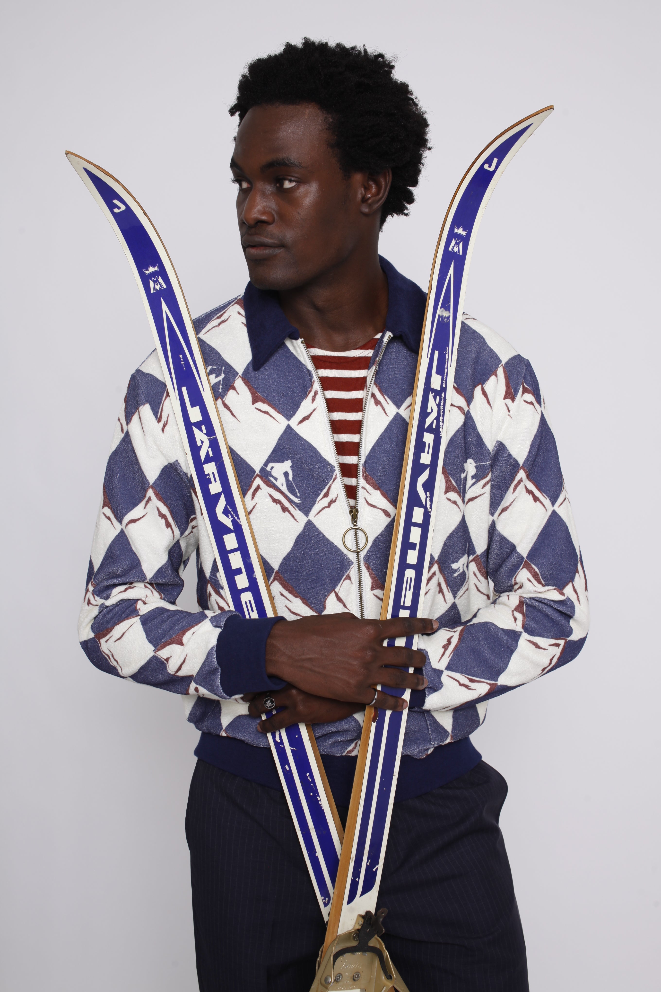 male model holding a pair of skies across his body