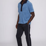 Male model wearing blue polo with traveler pants looking at camera