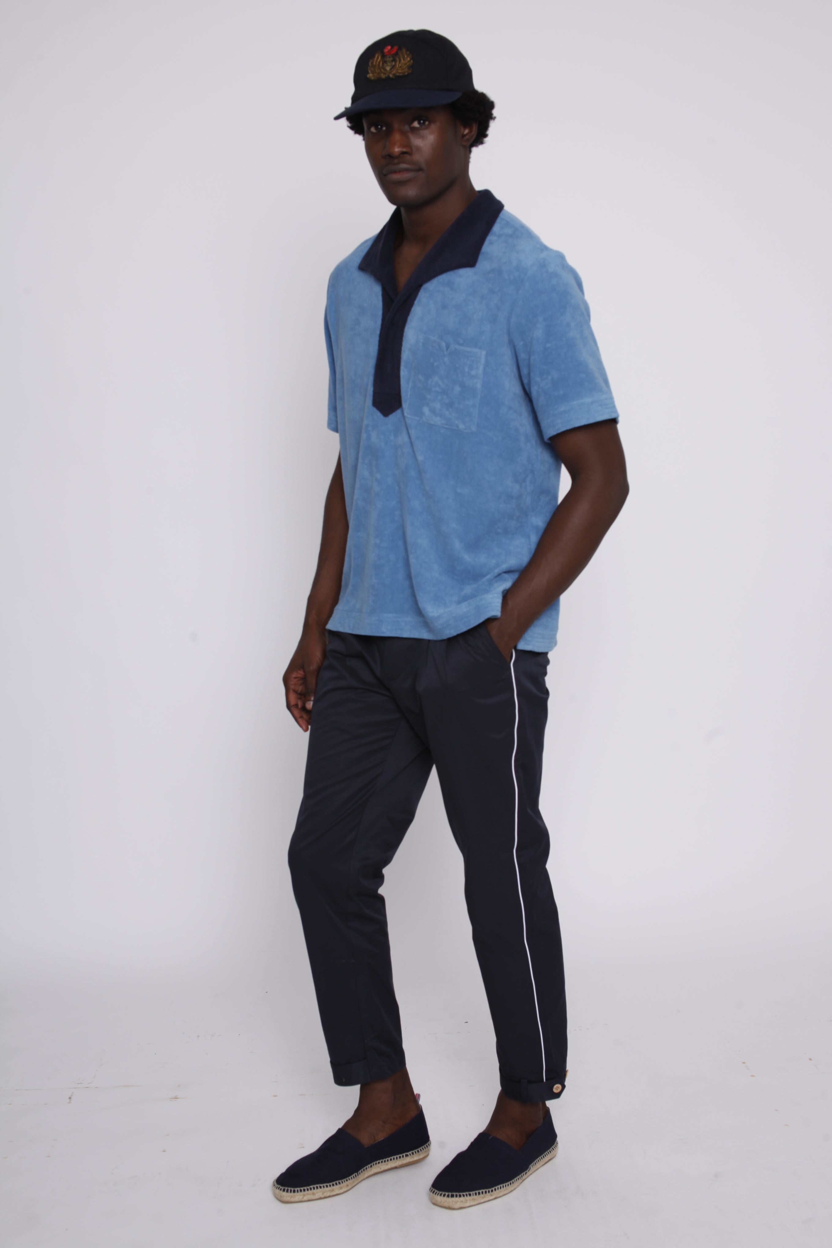 Male model wearing blue polo with traveler pants looking at camera