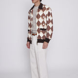 Man stands side on and looks off camera wearing unzipped cabana jacket