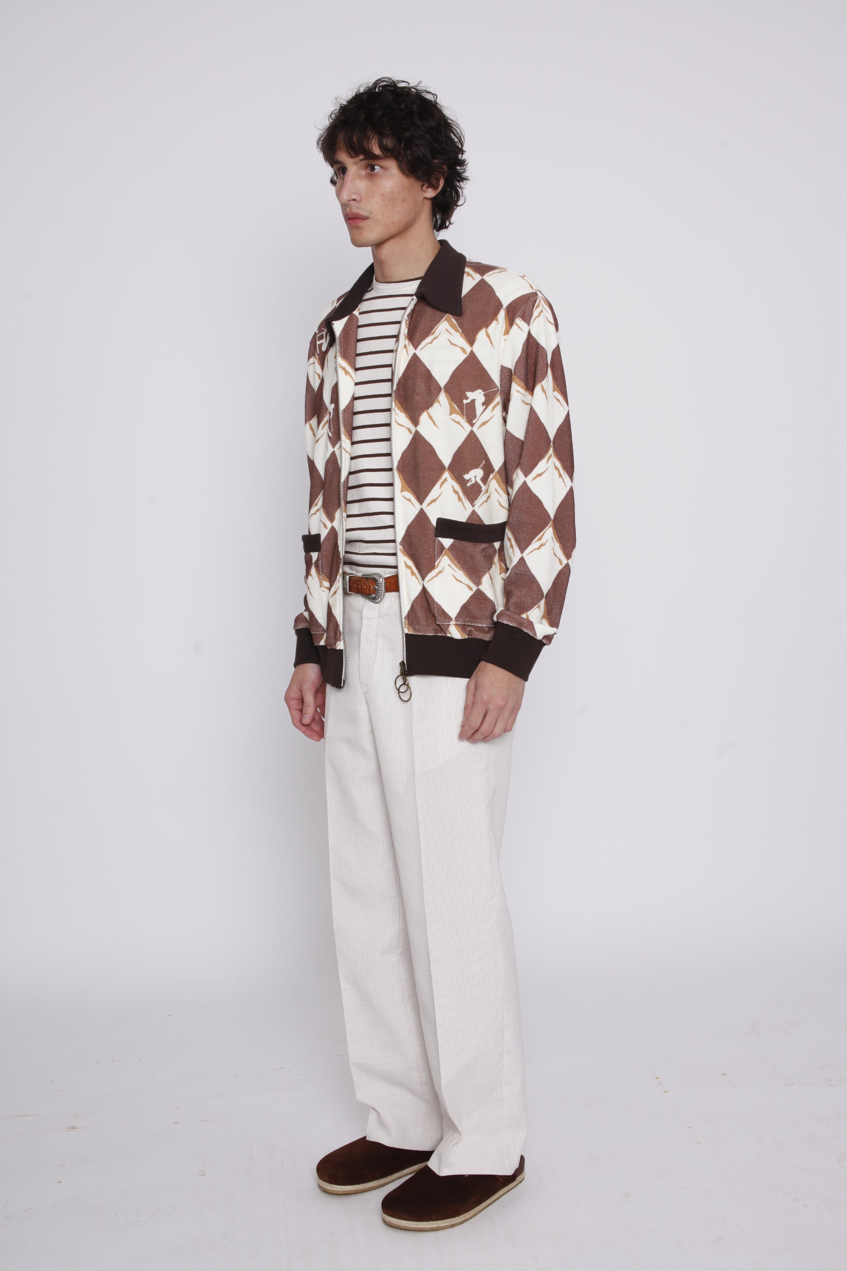 Man stands side on and looks off camera wearing unzipped cabana jacket