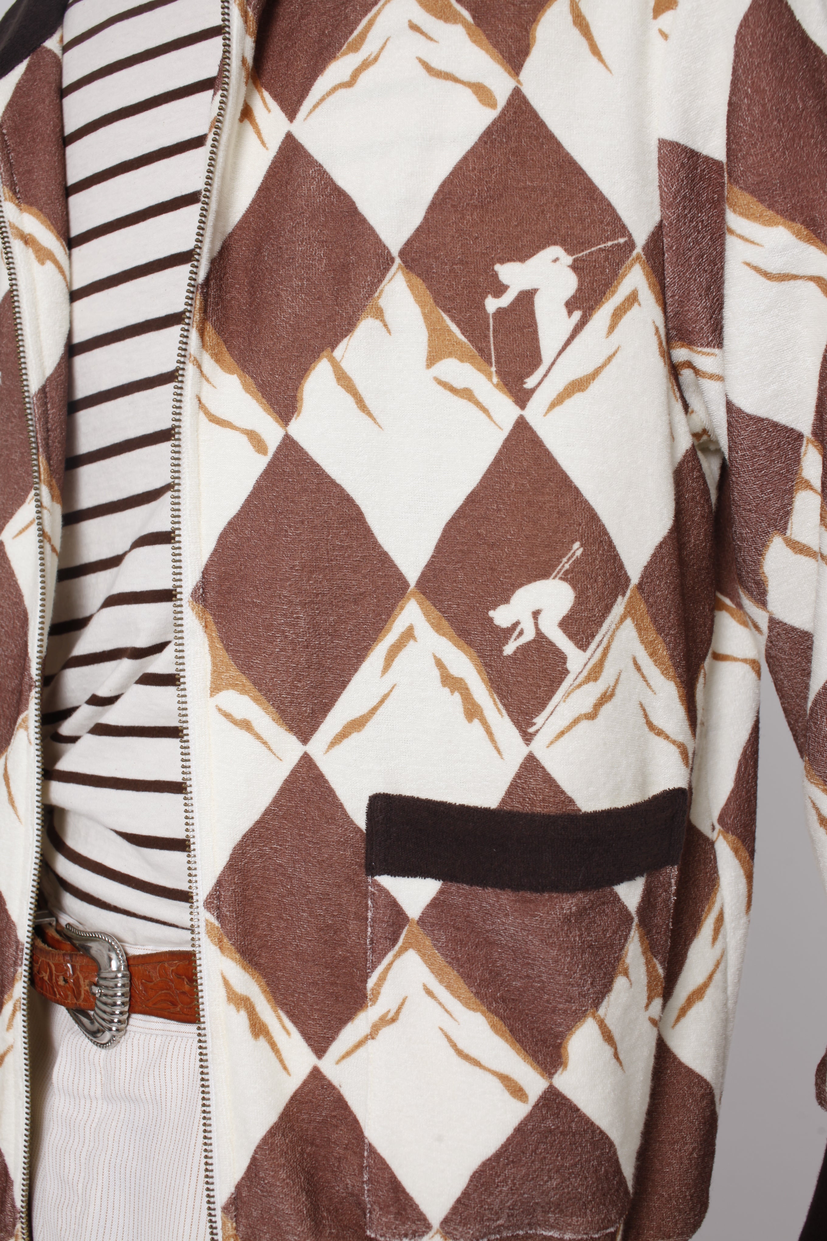 Close up of unzipped jacket showing skier motifs and pocket with black top lining