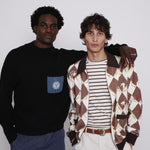 Man places both hands in pocket while another man puts arm around his shoulders