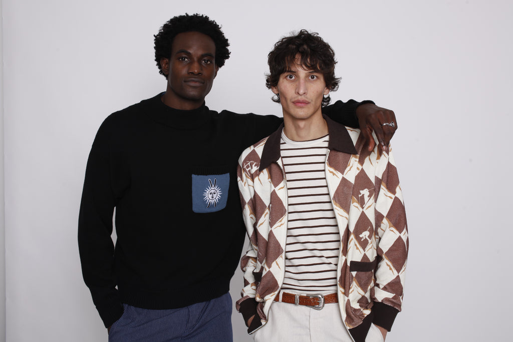 Man places both hands in pocket while another man puts arm around his shoulders