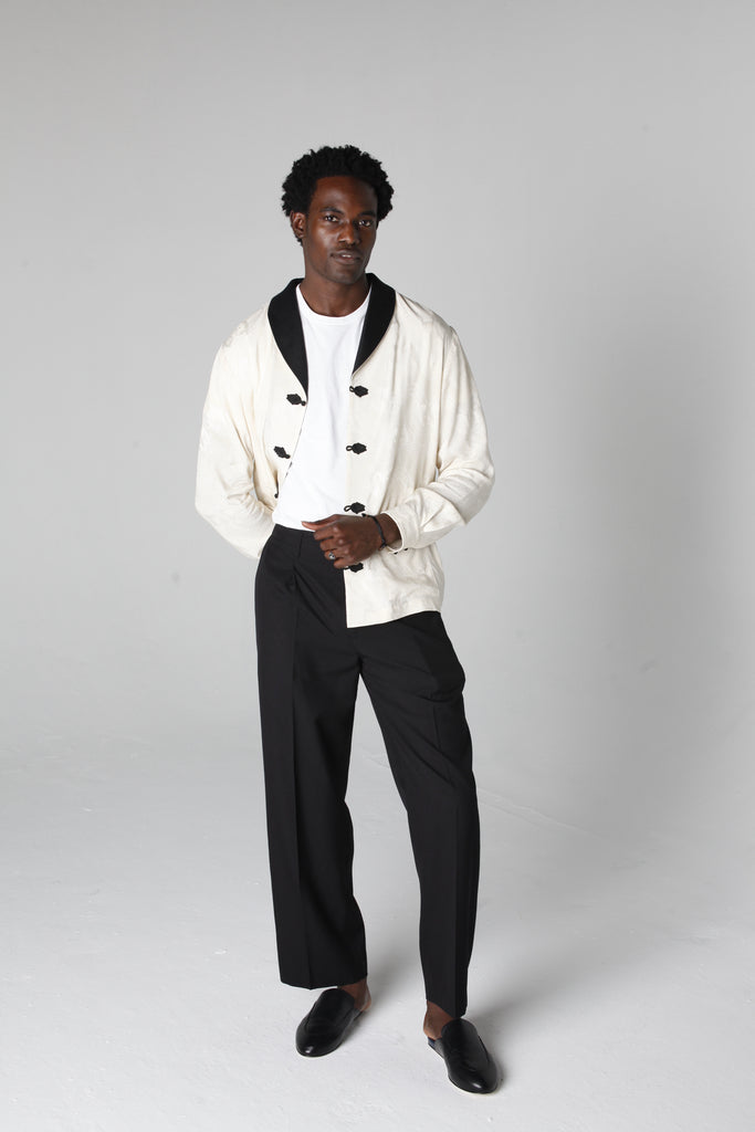 Man in studio wearing unbuttoned jacket with black pants