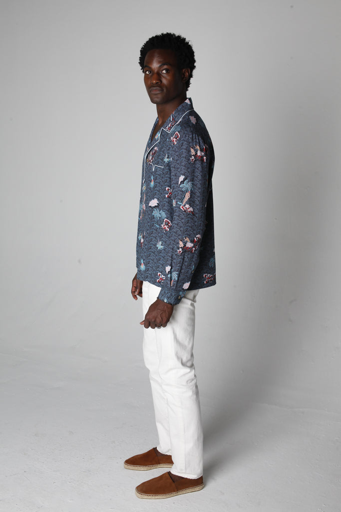 male model wearing top with white pants looking over his right shoulder in a photo studio