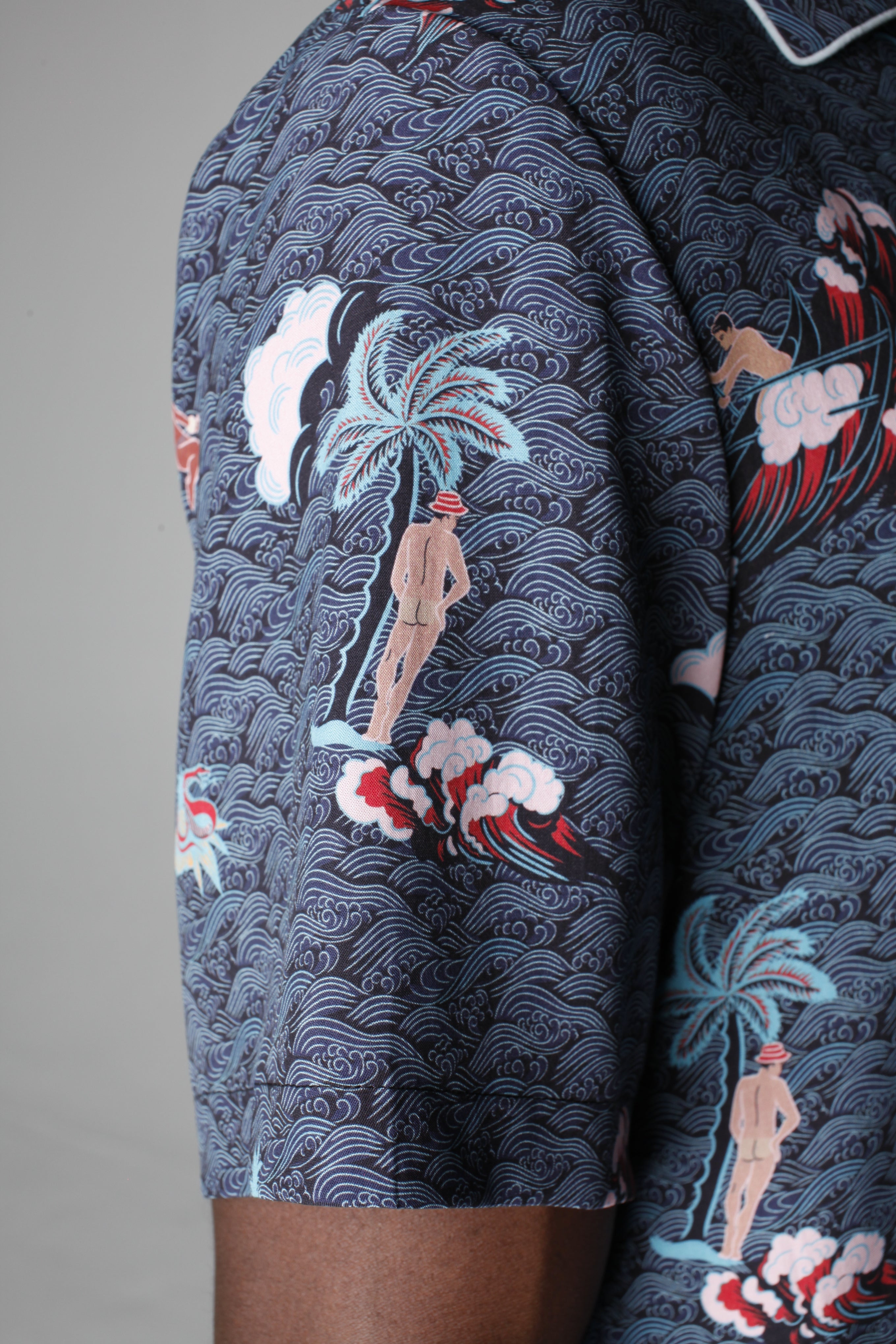 Close up of left sleeve showing the print with a naked backside Adam leaning on a palm tree