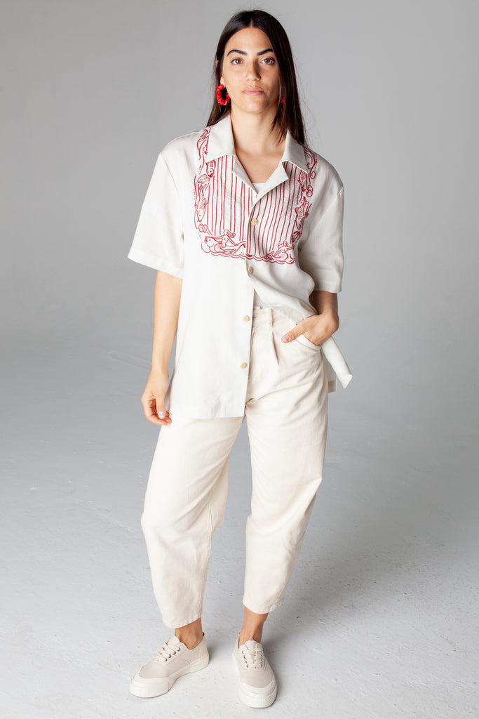 Female model wearing shirt with off white pants and red earrings