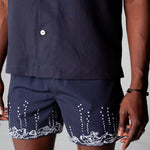 male model wearing navy swim trunks with navy button down