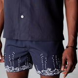 male model wearing navy swim trunks with navy button down
