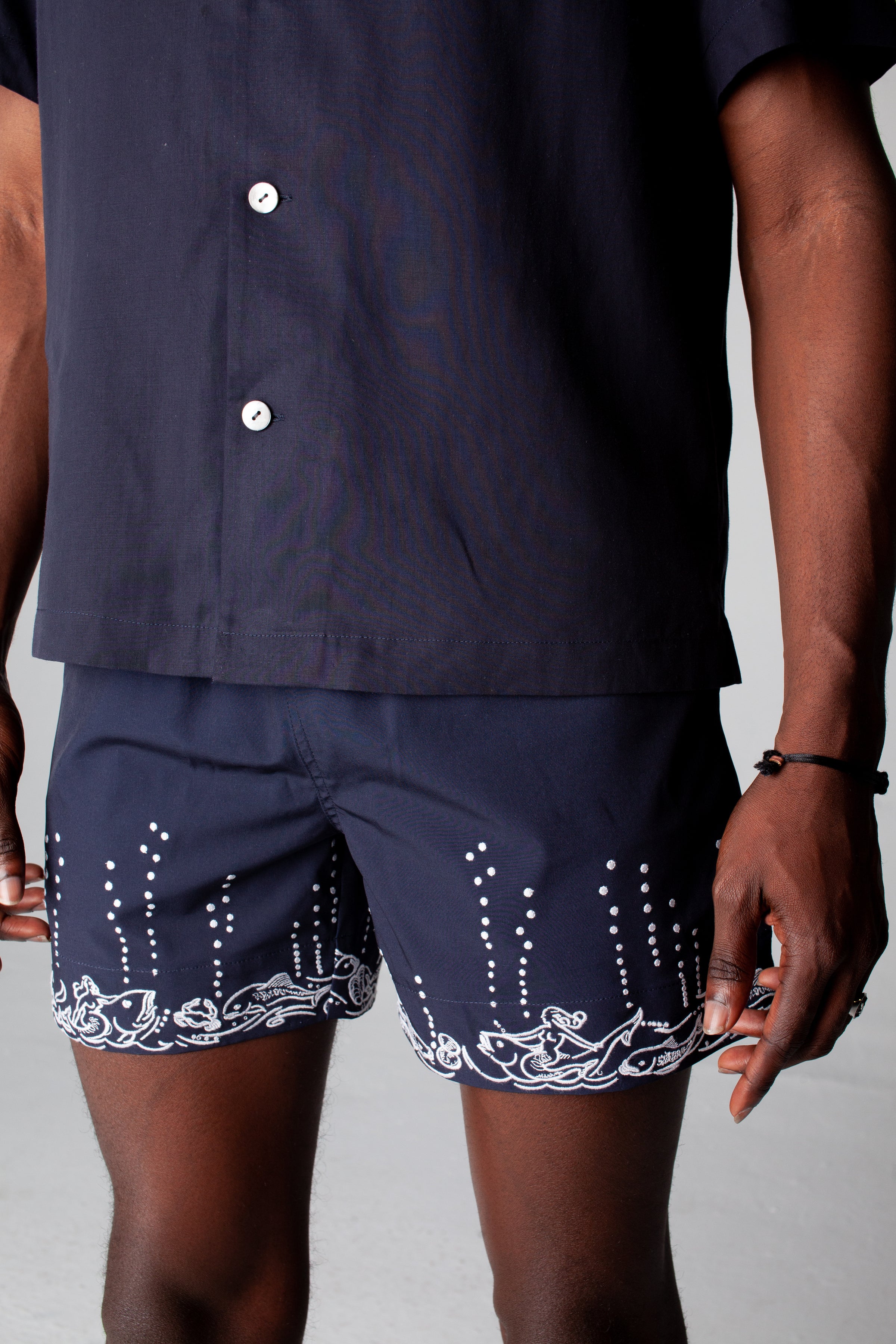 male model wearing navy swim trunks with navy button down