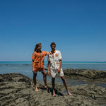 male and female models standing on rocks at the beach wearing the crouching tiger cabana sets