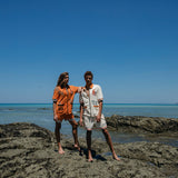 male and female models standing on rocks at the beach wearing the crouching tiger cabana sets