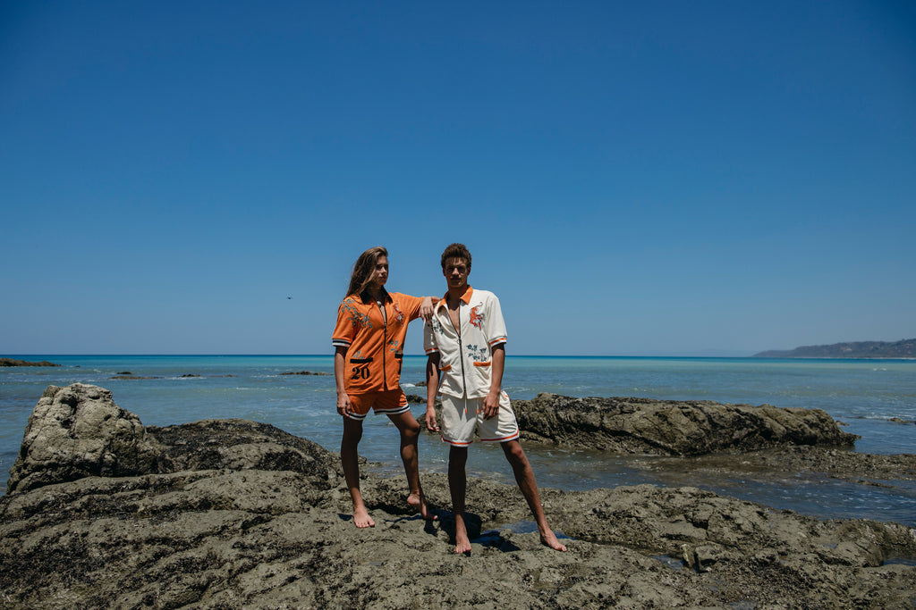 male and female models standing on rocks at the beach wearing the crouching tiger cabana sets