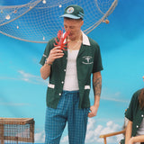 Male model in shirt holding up a toy lobster pretending to get pinched on the nose while a female model looks on
