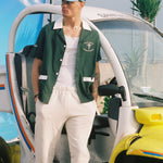 Male model leaning on a sanitation car in the shirt over an otherwise all white outfit