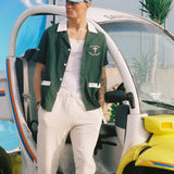 Male model leaning on a sanitation car in the shirt over an otherwise all white outfit